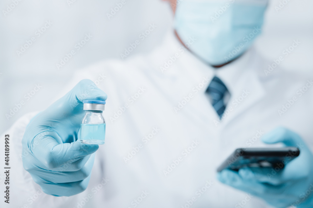 A doctor or scientist in the COVID-19 medical vaccine research and development laboratory holds a syringe with a liquid vaccine to study and analyze antibody samples for the patient. A doctor or scientist in the COVID-19 medical vaccine research and development laboratory holds a syringe with a liquid vaccine to study and analyze antibody samples for the patient.