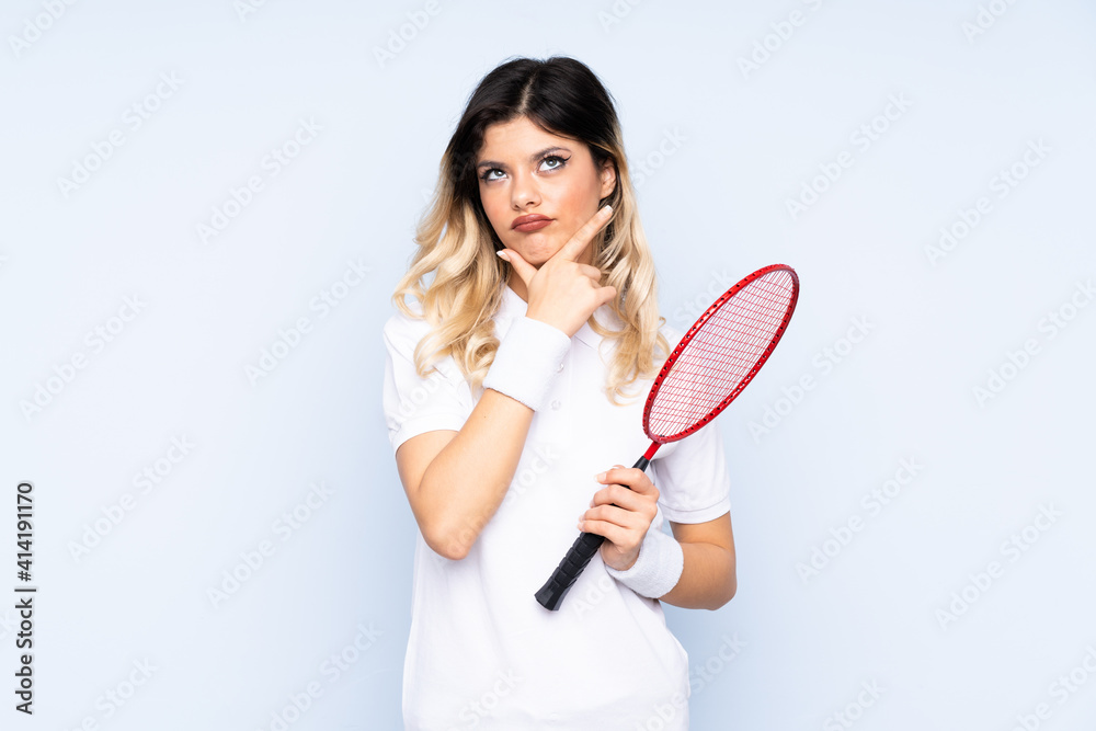 Teenager girl playing badminton isolated on blue background thinking an idea Teenager girl playing badminton isolated on blue background thinking an idea