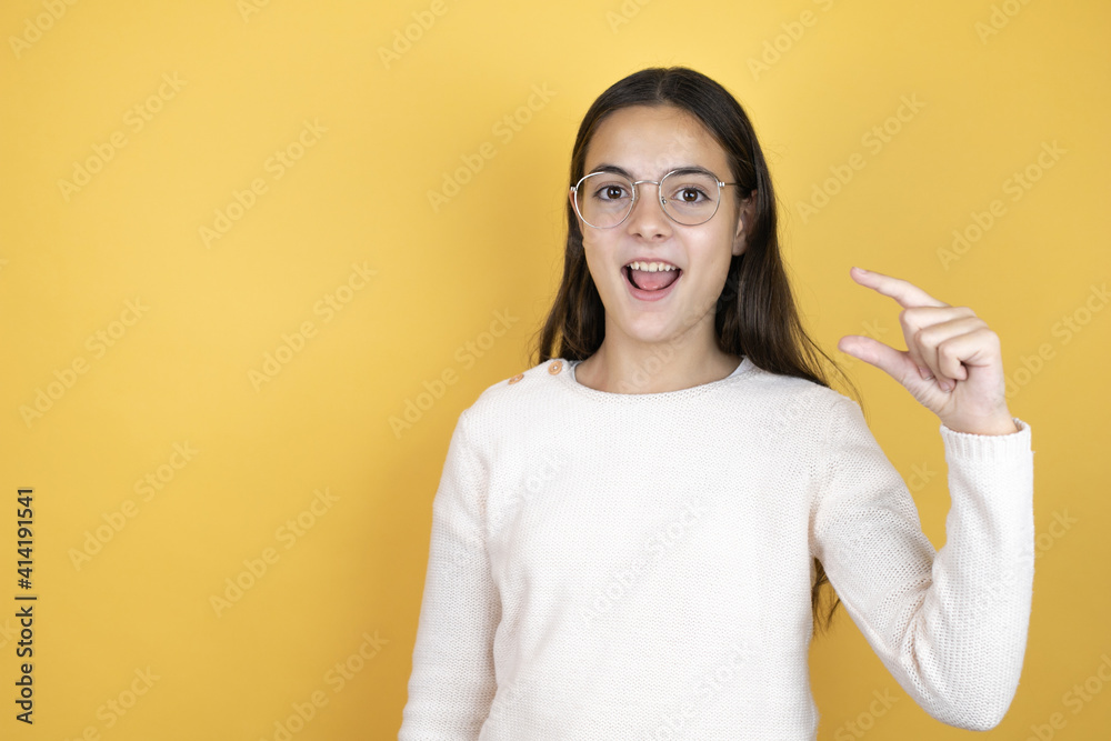 Beautiful child girl wearing casual clothes smiling and confident gesturing with hand doing small size sign with fingers . Measure concept.