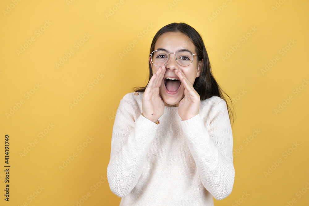 Beautiful child girl wearing casual clothes shouting and screaming loud to side with hands on mouth Beautiful child girl wearing casual clothes shouting and screaming loud to side with hands on mouth