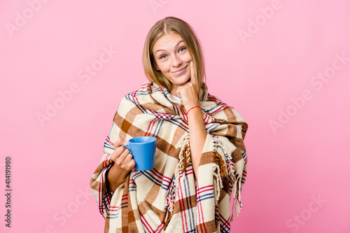 Young russian woman wrapped in a blanket drinking coffee doubting between two options.
