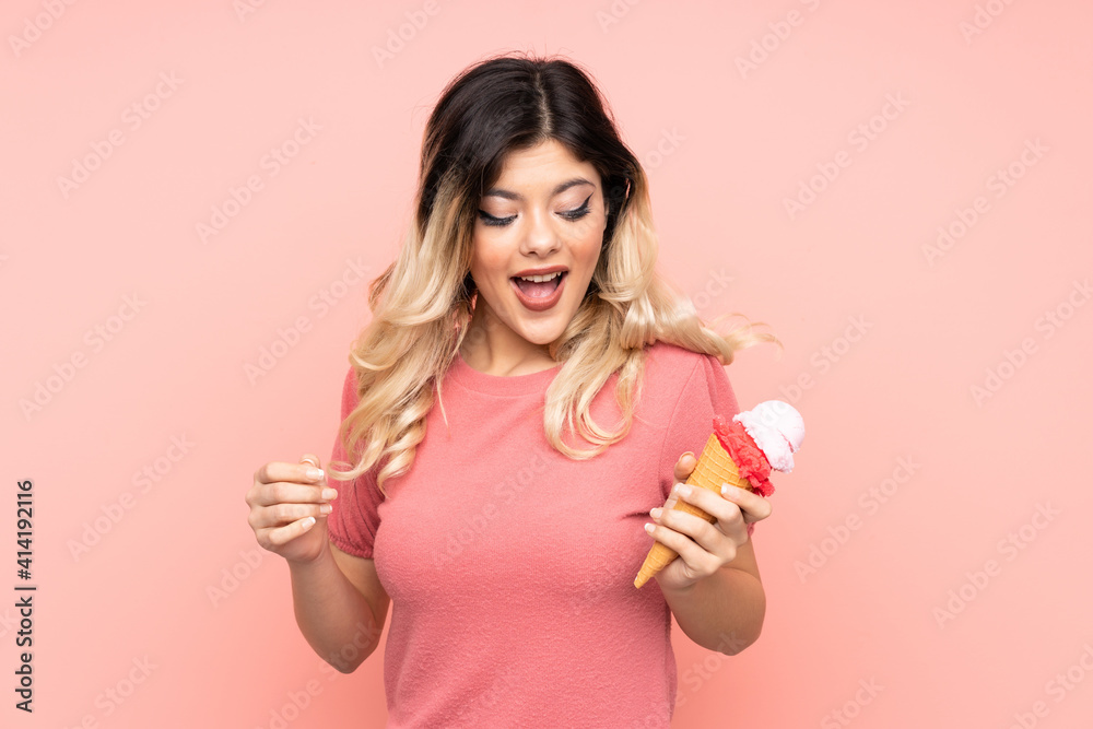 Teenager girl holding a cornet ice cream isolated on pink background with surprise and shocked facial expression Teenager girl holding a cornet ice cream isolated on pink background with surprise and shocked facial expression
