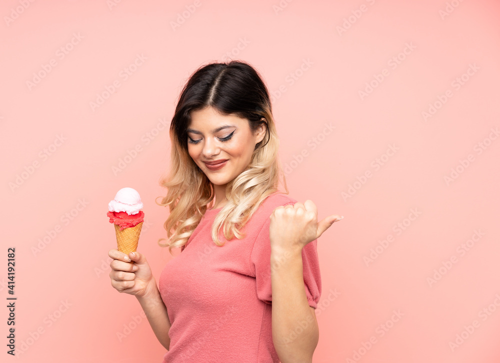Teenager girl holding a cornet ice cream isolated on pink background celebrating a victory Teenager girl holding a cornet ice cream isolated on pink background celebrating a victory