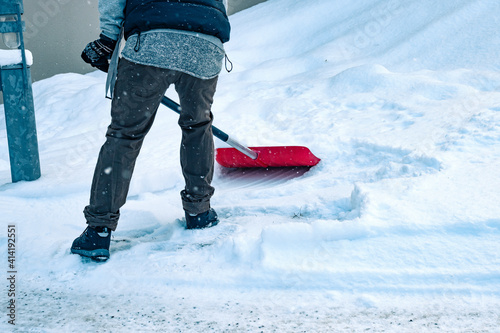 фотографія Man shoveling snow outside in winter time with a red snow shovel alone while it