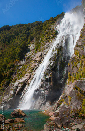 Fototapeta Naklejka Na Ścianę i Meble -  Waterfall flowing down mountain in Milford Sound fjord, Fiordland National Park, South Island, New Zealand.