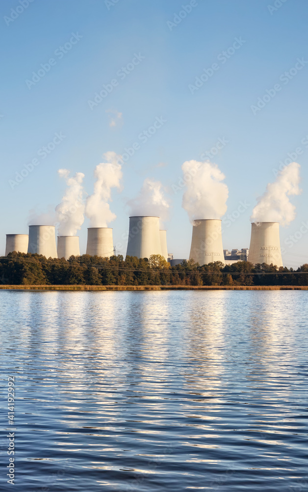 Power plant with smoking chimneys by a lake at sunset. Power plant with smoking chimneys by a lake at sunset.