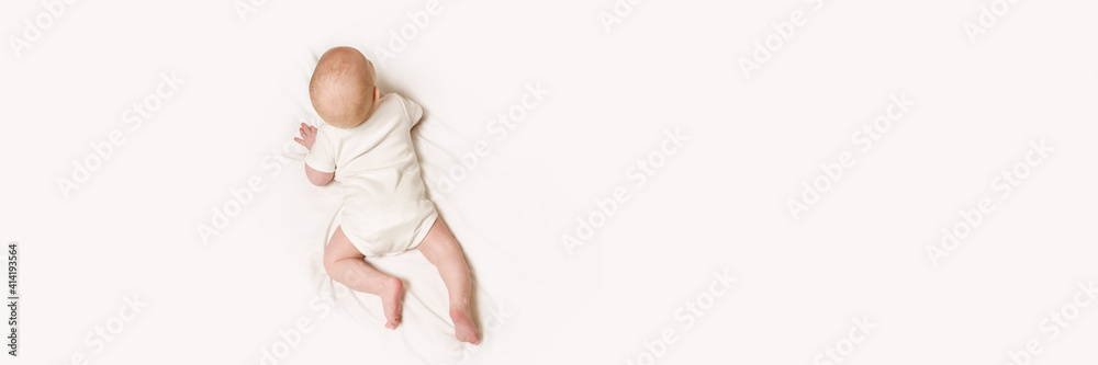 Cute small boy lying at bed. Back view. Body concept. Light background. Serious child. Copyspace. Stay home. Onesie mockup. Horizontal banner. White clothes Cute small boy lying at bed. Back view. Body concept. Light background. Serious child. Copyspace. Stay home. Onesie mockup. Horizontal banner. White clothes