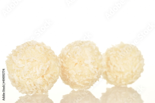 Several round sweets with coconut flakes, close-up, isolated on white.