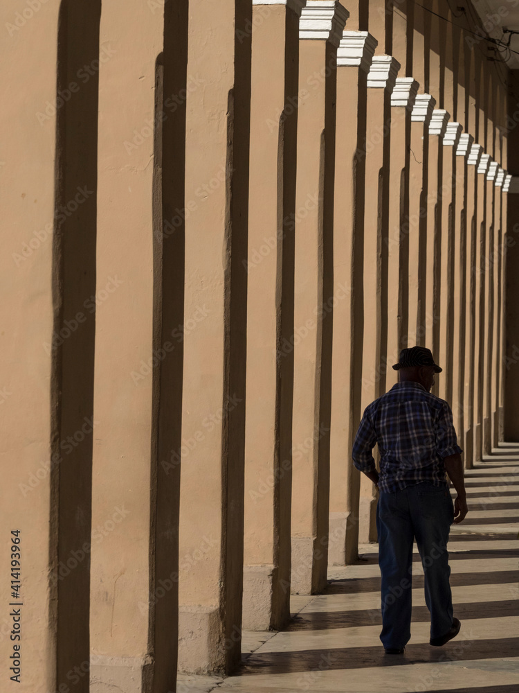 Cuba, Cienfuegos, man walking in colonnade.