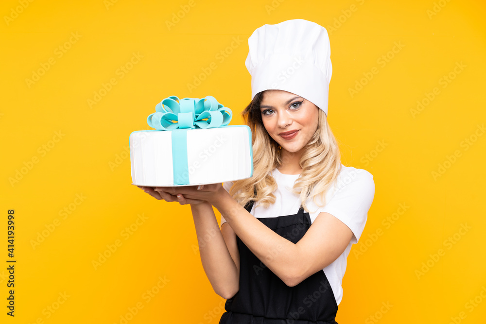 Teenager girl pastry holding a big cake isolated on yellow background Teenager girl pastry holding a big cake isolated on yellow background