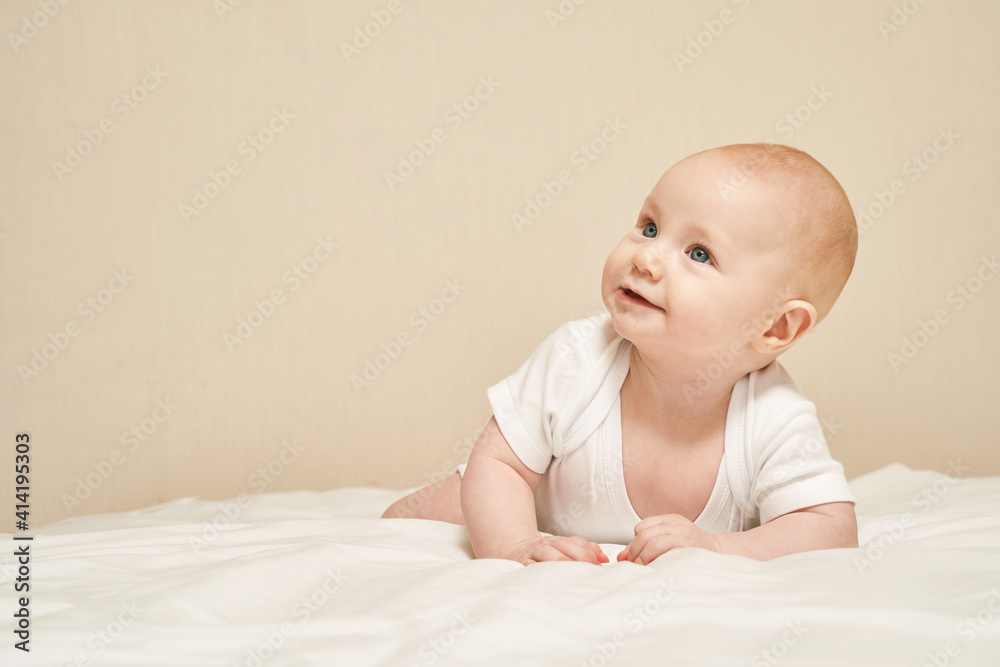 Cute small boy lying at bed. Childhood concept. Light background. Smiling child. Happy emotion. Copyspace. Stay home. Mockup. White clothes Cute small boy lying at bed. Childhood concept. Light background. Smiling child. Happy emotion. Copyspace. Stay home. Mockup. White clothes