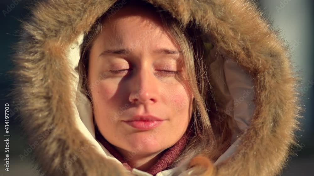 Happy woman wearing white winter coat resting outside in the sun Happy woman wearing white winter coat resting outside in the sun