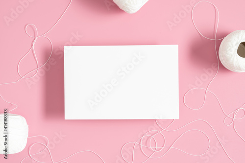 White paper empty blank, twine on pastel pink background. Invitation card mockup on pink table. Flat lay, top view, copy space, mockup