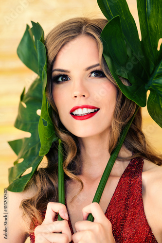 Pretty woman with healthy clear skin holding green leaves