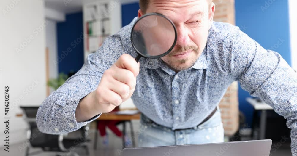 Young businessman looking at camera with magnifier in office 4k movie. Developing right business strategy concept