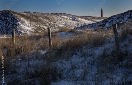 Lighthouse. Dunes with snow. Julianadorp Northsea coast Netherlands. Fencepole. Winter. photo