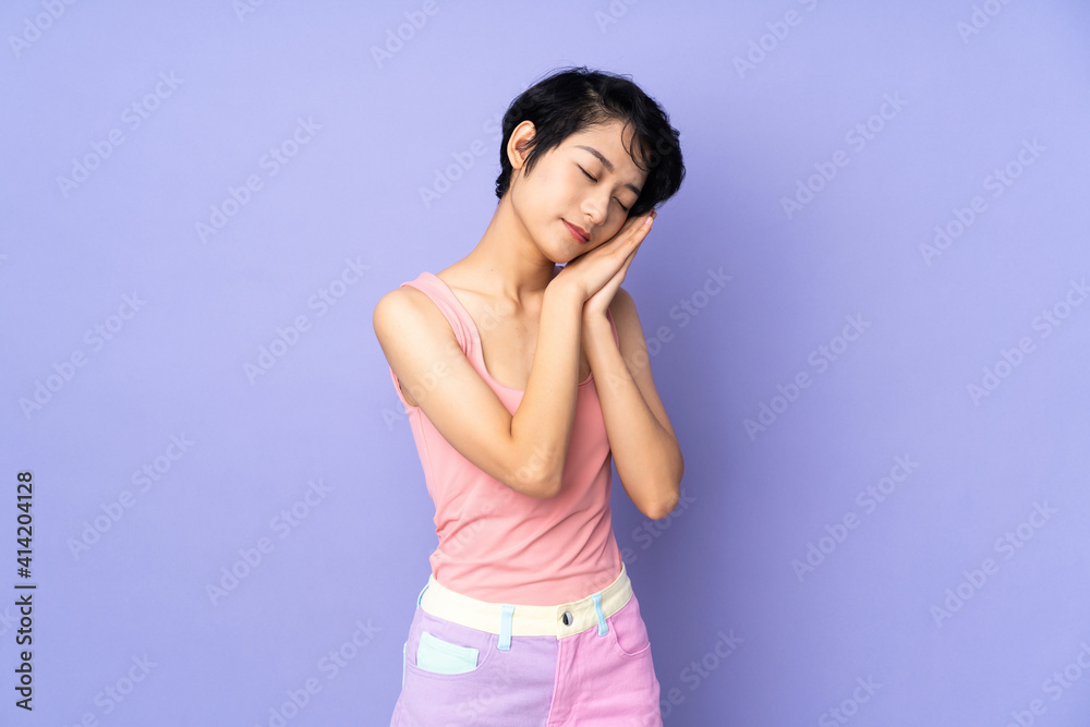 Young Vietnamese woman with short hair over isolated purple background making sleep gesture in dorable expression Young Vietnamese woman with short hair over isolated purple background making sleep gesture in dorable expression