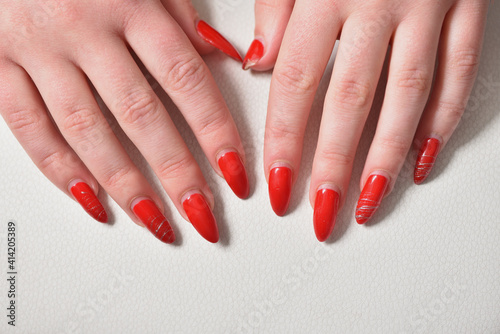 Female hands with regrown red gel nails close-up