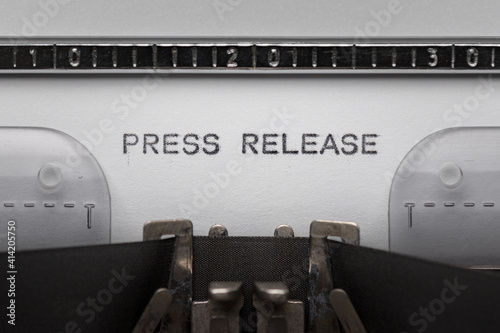 Typing text PRESS RELEASE on vintage manual typewriter. Close up of writes word on white paper. Shot in macro.