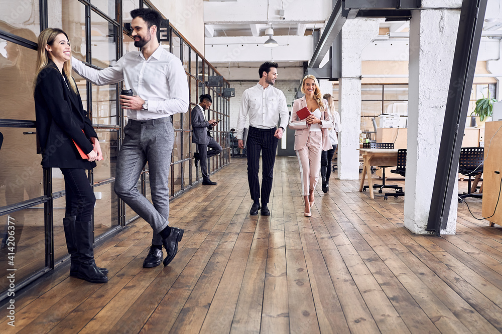 Obraz premium On the way to business meeting. Full length of young modern people in formal wear having a discussion while walking through the office. A couple of freelancers are discussing new ideas.