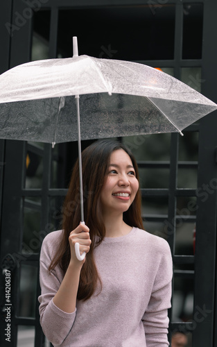 Asian woman holding umbrella in raining season