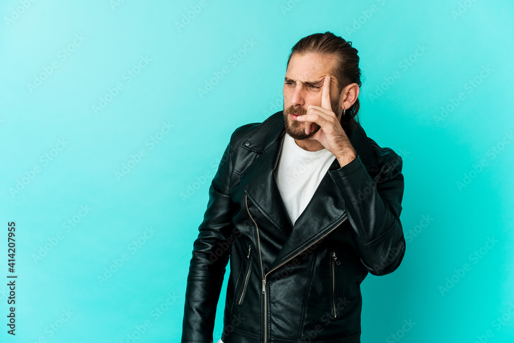 Young man with long hair look pointing temple with finger, thinking, focused on a task. Young man with long hair look pointing temple with finger, thinking, focused on a task.