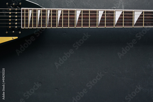 Top view crop shot of black V shape electric guitar on dark grunge background with copy space 