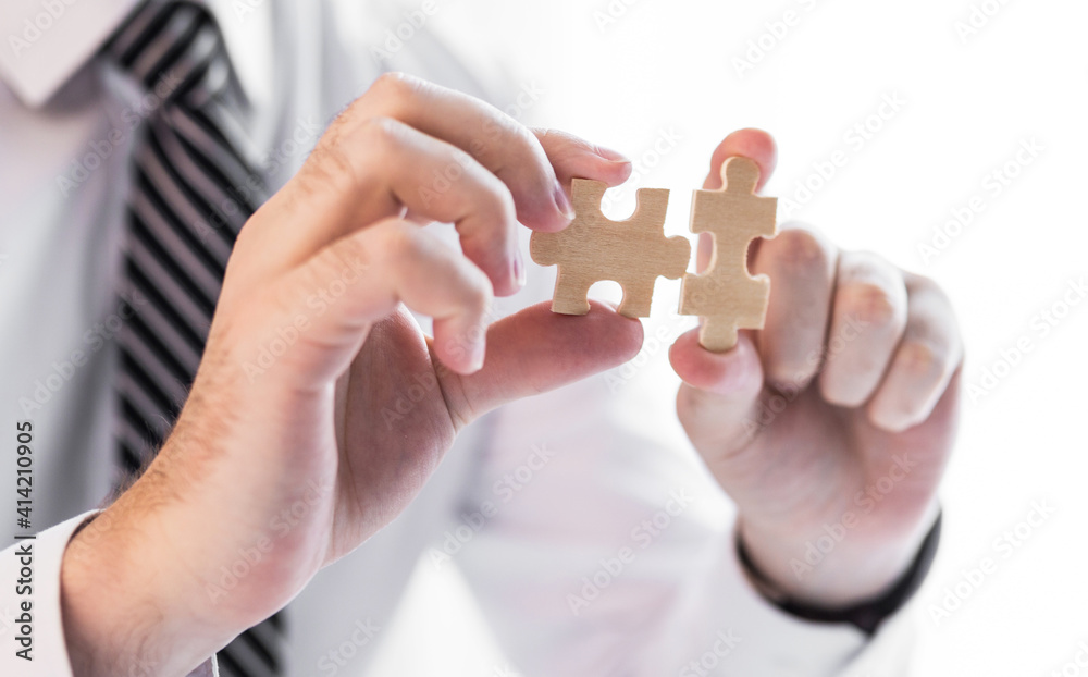 Businessman hand connecting jigsaw puzzle.Business solutions, success and strategy concept.