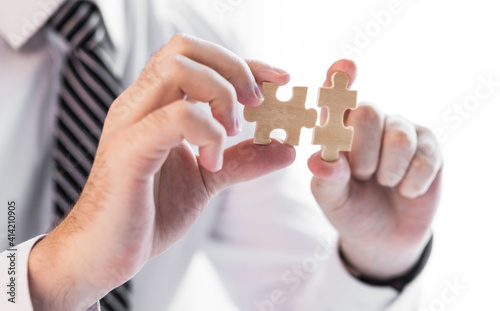 Businessman hand connecting jigsaw puzzle.Business solutions, success and strategy concept.