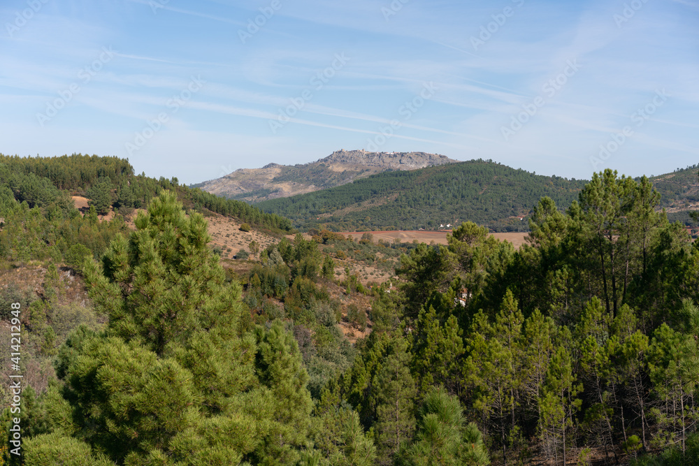 View of Marvao village on top of the mountain range on the middle of the trees landscape on a sunny day in Alentejo, Portugal