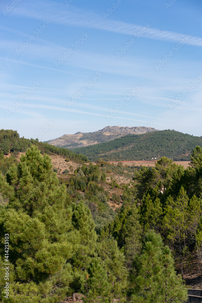 View of Marvao village on top of the mountain range on the middle of the trees landscape on a sunny day in Alentejo, Portugal