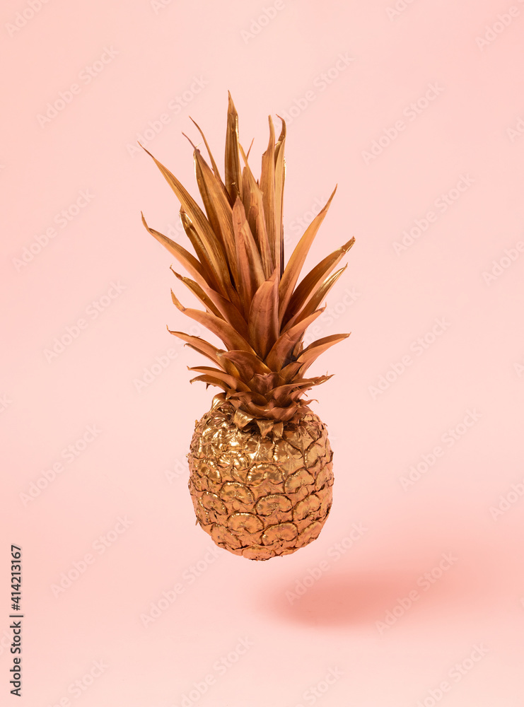 flying golden fresh pineapple on pink background. abstract lovely concept.