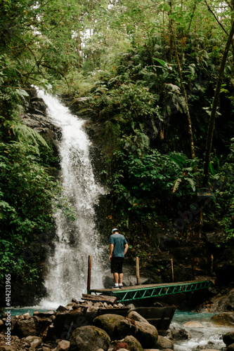 Stack photo of unrecognized man admiring an amazing waterfall in Costa Rica.