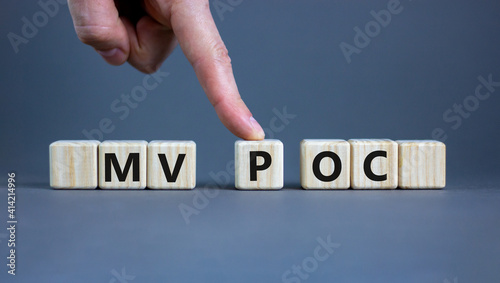 MVP vs POC symbol. Businessman pushes the cube with words MVP, minimum viable product and POC, proof of concept. Beautiful grey background. Business and MVP vs POC concept, copy space.