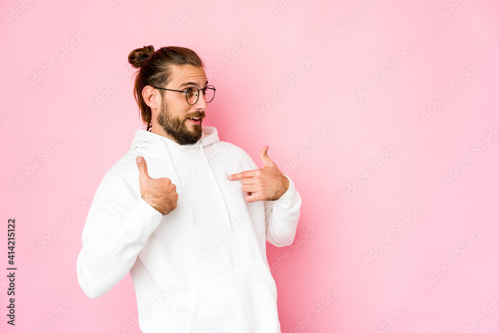 Young man with long hair look surprised pointing with finger, smiling broadly. Young man with long hair look surprised pointing with finger, smiling broadly.