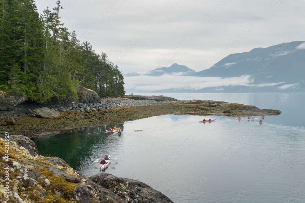 Canada, British Columbia. Sea kayakers paddle along the shore of Hansen Island in Johnstone Strait.