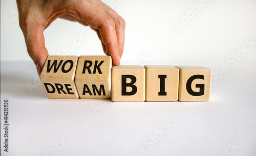 Work or dream big symbol. Businessman turns wooden cubes, changes words 'dream big' to 'work big'. Beautiful white table, white background, copy space. Business and dream or work big concept.