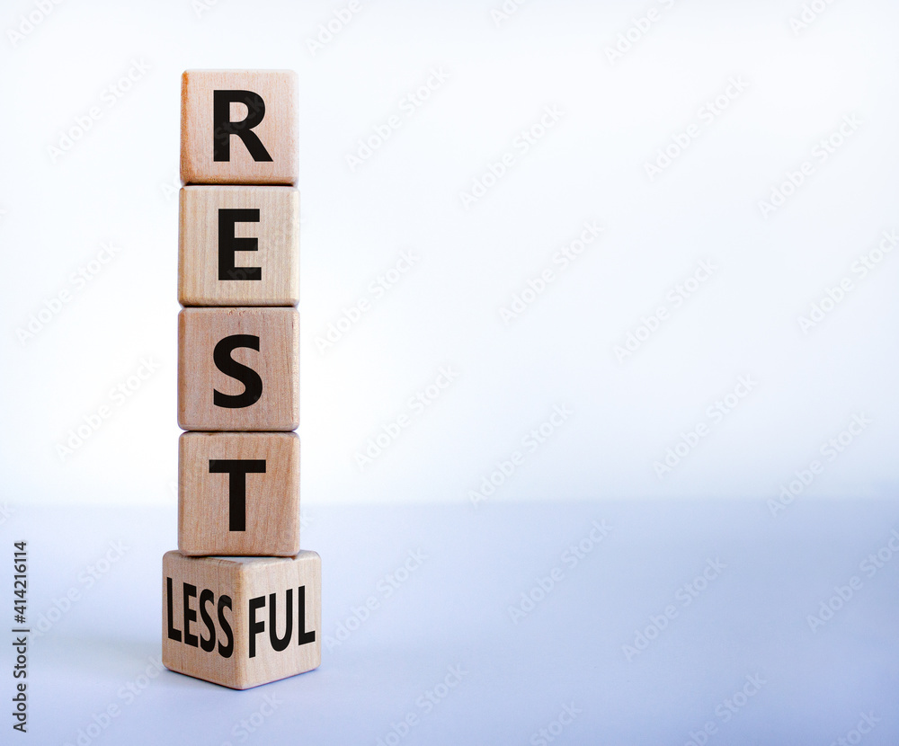 Restless or restful symbol. Turned the wooden cube, changed the word 'restless' to 'restful'. Beautiful white table, white background, copy space. Business and restless or restful concept. Restless or restful symbol. Turned the wooden cube, changed the word 'restless' to 'restful'. Beautiful white table, white background, copy space. Business and restless or restful concept.
