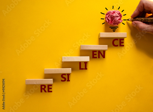 Business and resilience symbol. Wood blocks stacking as step stair, yellow background, copy space. Businessman hand. Word 'resilience'. Conceptual image of motivation. Business and resilience concept. photo