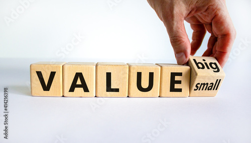 Small or big value symbol. Businessman turns wooden cubes and changes words 'value small' to 'value big'. Beautiful white background, copy space. Business and small or big value concept.