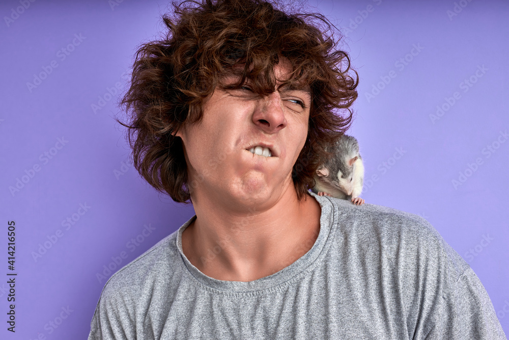 guy makes funny grimace face while his lovely pet rat crawling on him, emotional guy with decorative mouse guy makes funny grimace face while his lovely pet rat crawling on him, emotional guy with decorative mouse