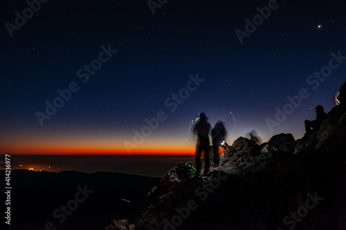 Tourists with headlamps at dawn waiting for sunrise at Pico del Teide mountain in El Teide National park. Tenerife, Canary Islands, Spain