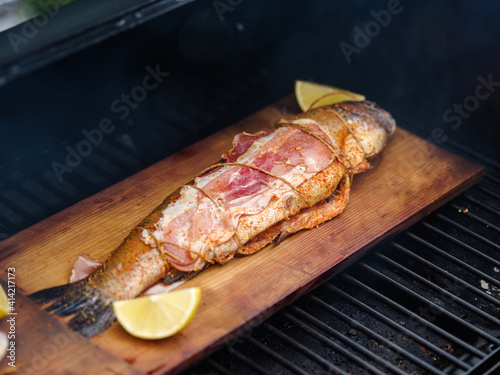 Trout on a cedar plank with lemon and bacon grilled.
