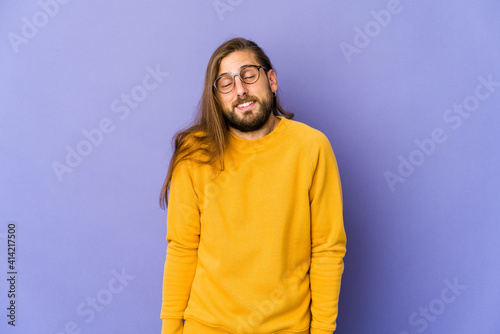 Young man with long hair look laughs and closes eyes, feels relaxed and happy.