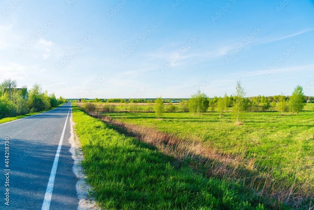 Spring landscape with rural asphalt road with greenery on the sides Spring landscape with rural asphalt road with greenery on the sides
