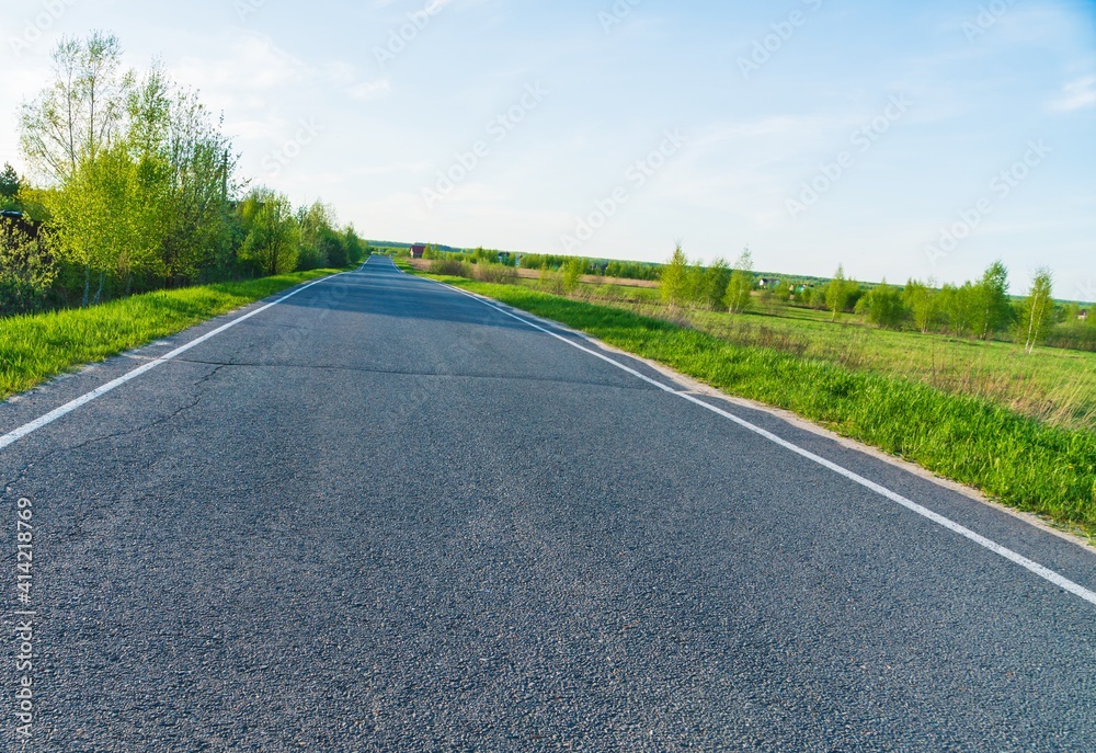 Spring landscape with rural asphalt road with greenery on the sides Spring landscape with rural asphalt road with greenery on the sides