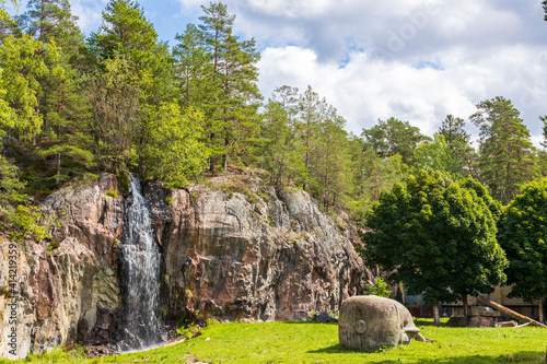 Gorgeous natural landscape view. Small waterfall on rocky landscape and green plants on background. Sweden.
