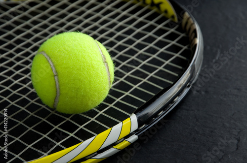 Yellow Tennis Ball with Black and Yellow Racquet on Dark Background