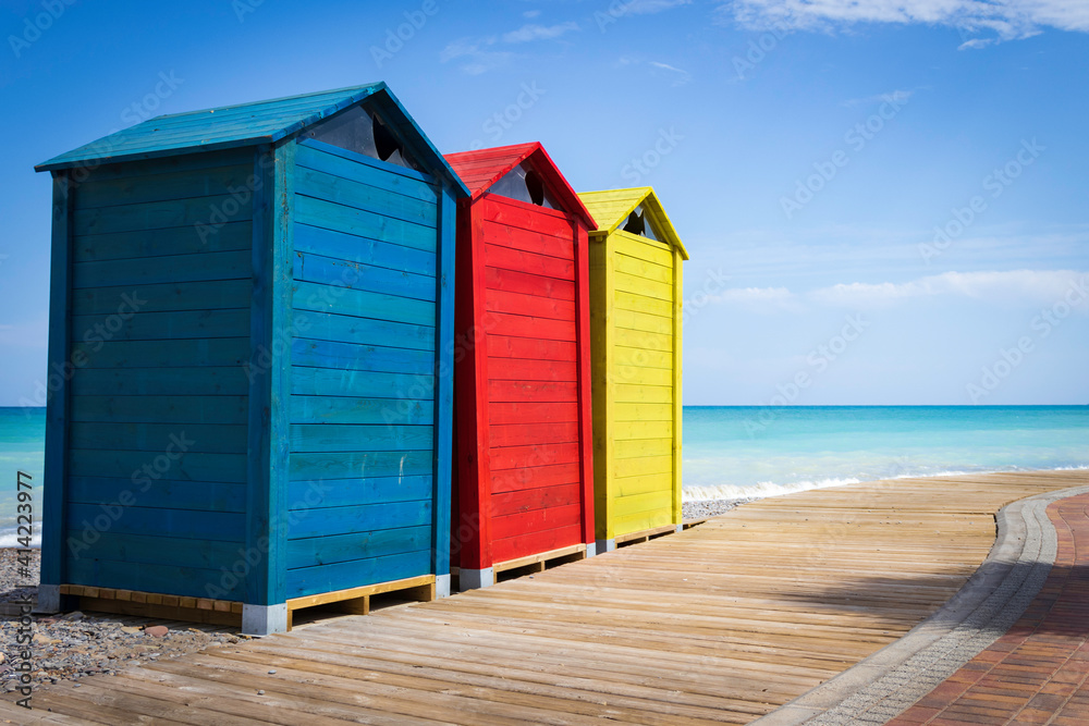 Naklejka premium Colorful huts on the way to wood on the beach