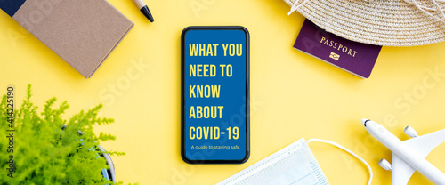 Obraz na płótnie Flat lay, an aircraft model, sun hat, protective face mask, passport and a smartphone with ‘What you need to know about Covid-19, a guide to staying safe’ note, are arranged on a yellow background. w salonie